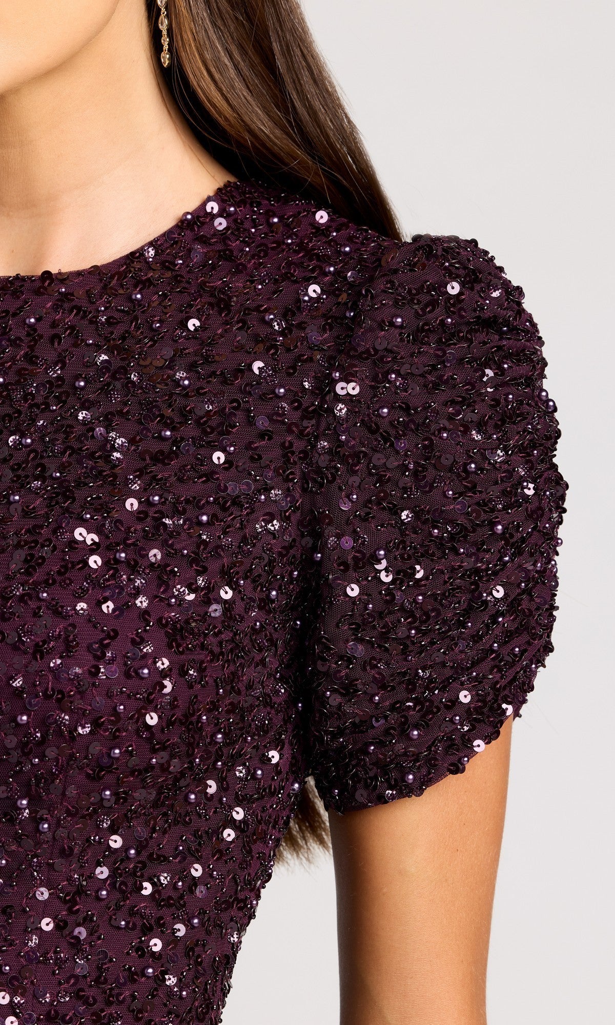 Close-up of a person wearing the Mac Duggal 24003 Short Sleeve Sequin Formal Dress in dark purple, featuring puffed short sleeves and shimmering sequins, shown from shoulder to mid-torso.